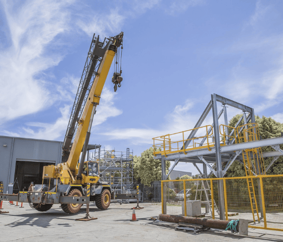 C1 Crane being operated at a warehouse facility with scaffolding structure in the background.