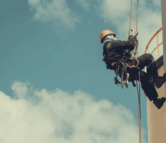 Harnessed man ascending up a building wall while practicing Work Safety at Heights.